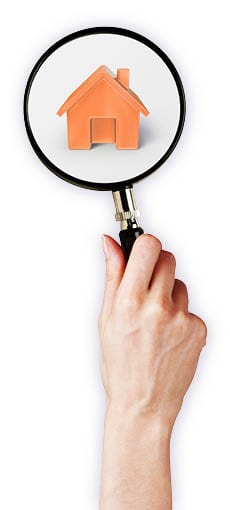 Hand holding a magnifying glass over an orange house